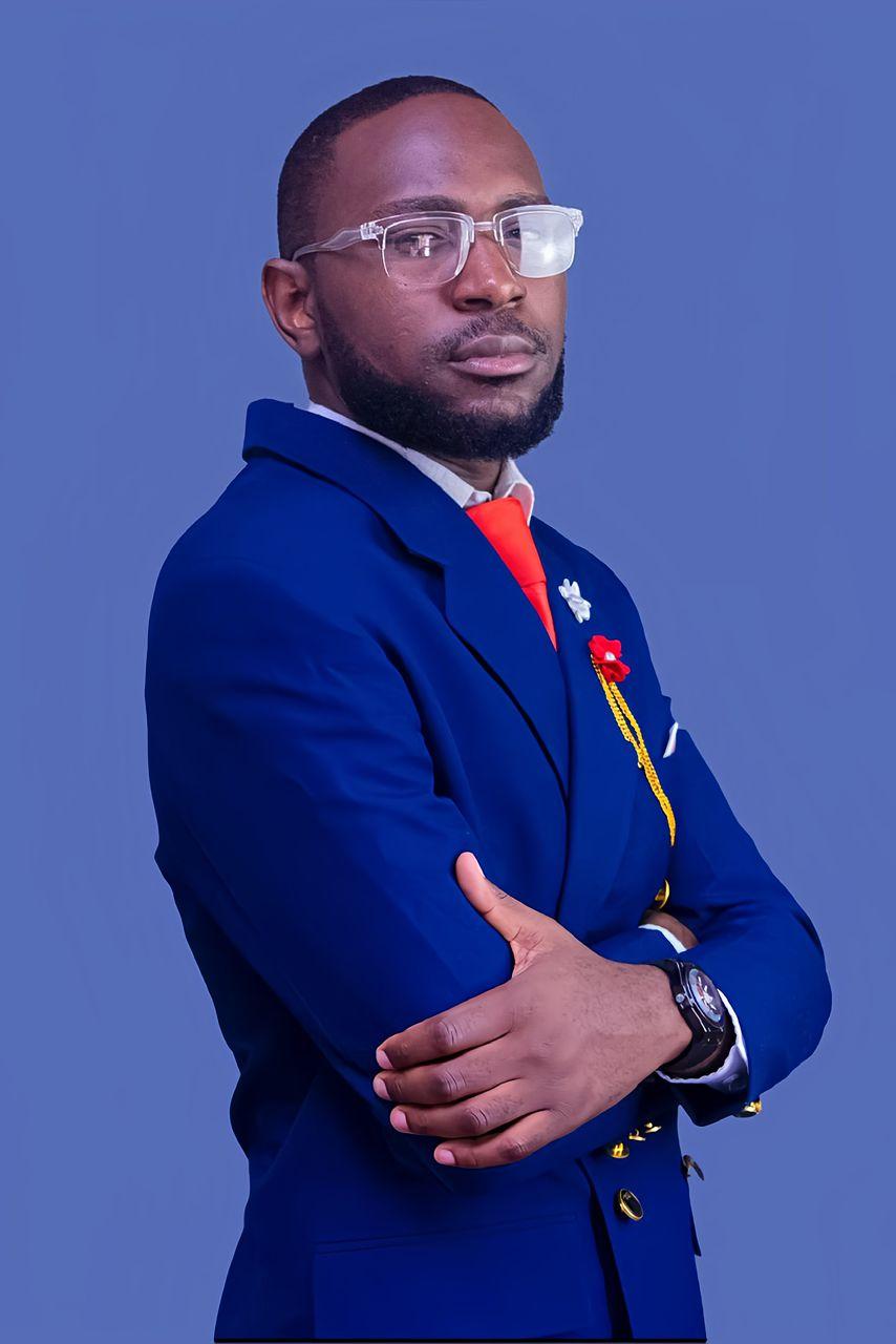 Patrick Mwewa in a royal blue double-breasted suit, arms folded